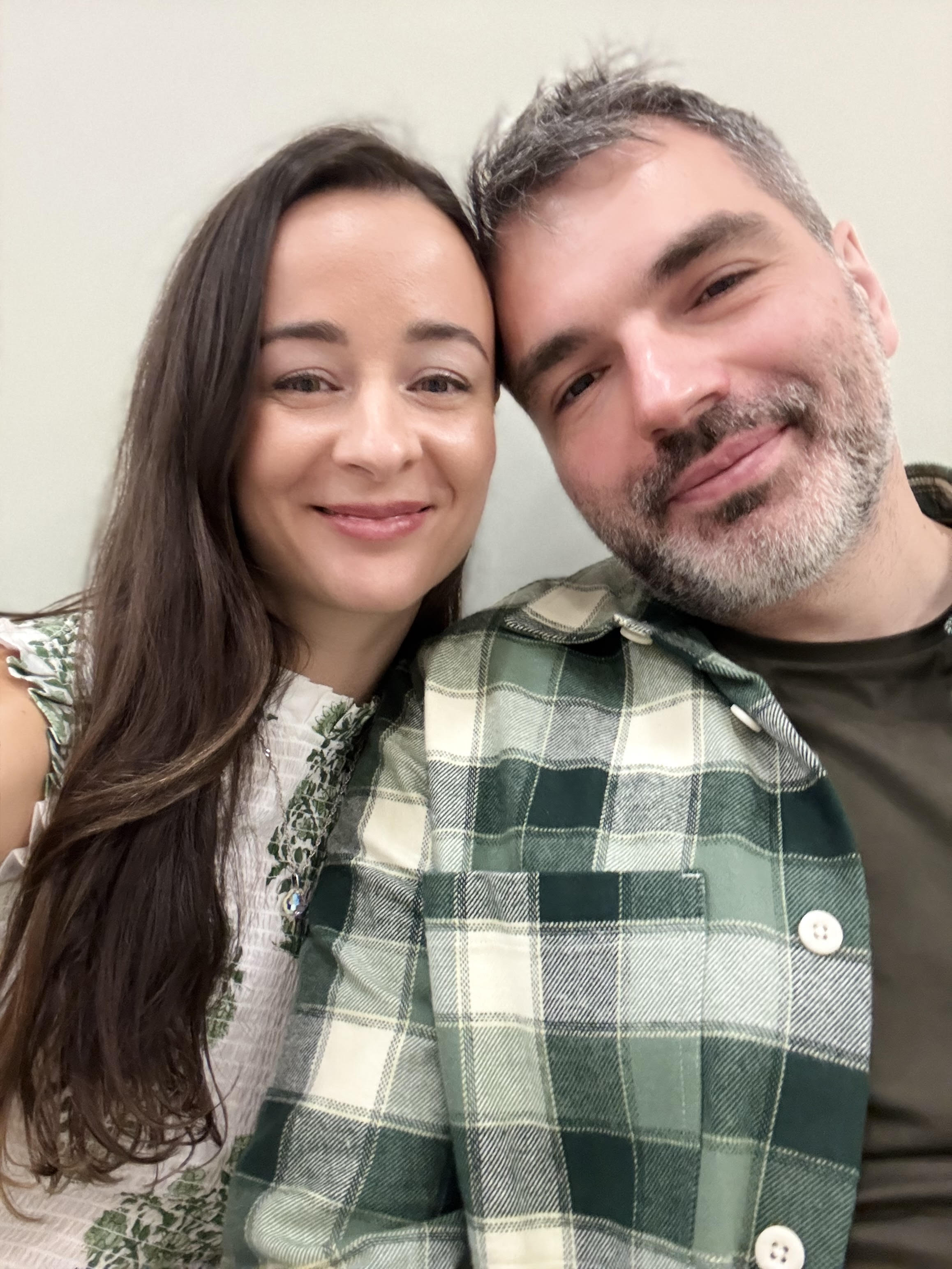 Aude and Ilian, the founders of Audela, in a close portrait. Aude on the left with long dark hair, Ilian on the right wearing a green plaid shirt.